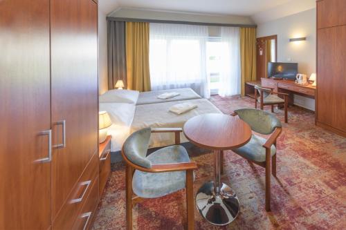 ein Hotelzimmer mit einem Bett und einem Tisch und Stühlen in der Unterkunft Ośrodek Wypoczynkowo-Rehabilitacyjny "Bryza" in Dźwirzyno