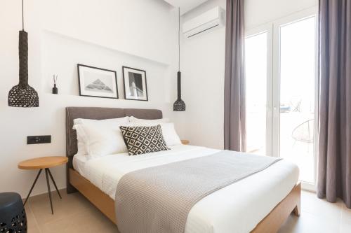 a white bedroom with a bed and a window at Eleana Hotel in Tinos Town