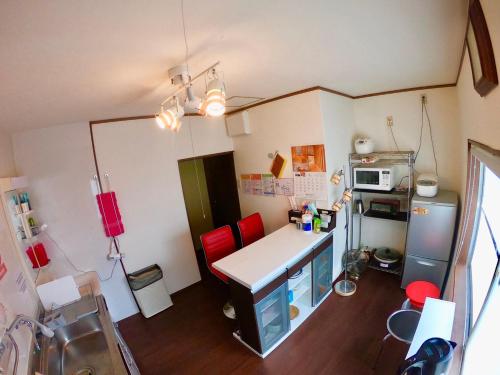 a small kitchen with a desk and red chairs at Benidaruma - Sakuramochi in Kyoto