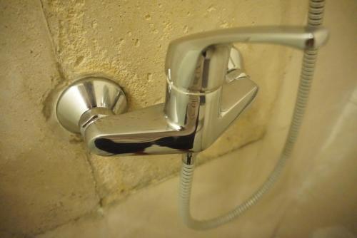 a metal faucet attached to a wall at Louto Dmell Villa & Guesthouse in Sanur