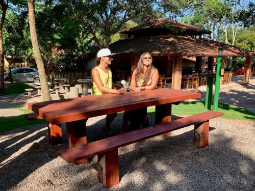 two women sitting at a picnic table in a park at Hotel São Sebastião da Praia in Florianópolis