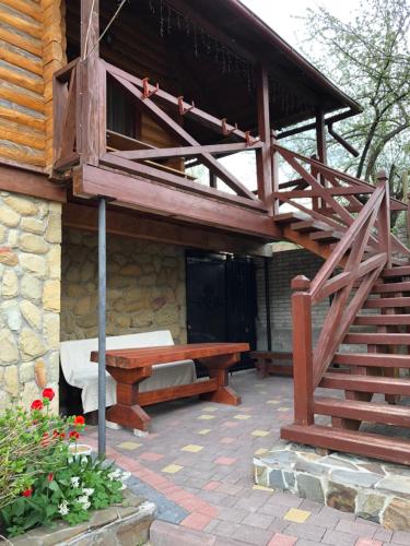 a patio with a wooden bench and a wooden stairs at Karpatska Mria in Yaremche
