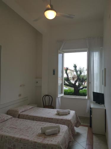 a bedroom with two beds and a window at Hotel Milani in Lido di Camaiore