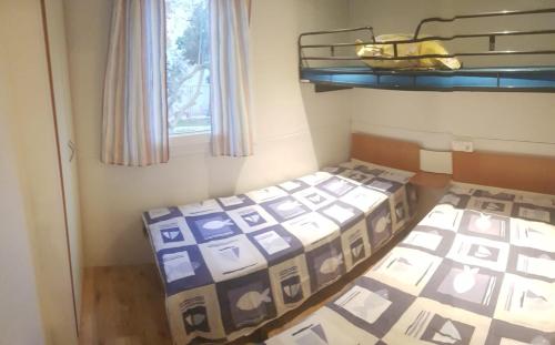 two beds in a small room with a window at Mobile homes Olive and Sea in Bibinje