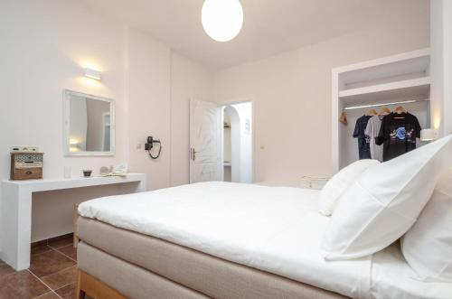 a white bedroom with a white bed and a mirror at Asterias Studios in Agia Anna Naxos