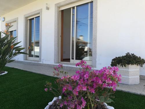 una casa blanca con flores púrpuras en un patio en Casa Carla, en Guimarães