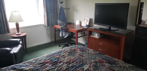 a hotel room with a bed and a desk with a television at Huntingdon Motor Inn in Huntingdon