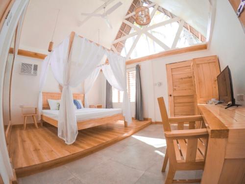 a bedroom with a bed with a window and a desk at Bermuda Triangle Bungalows in Siquijor