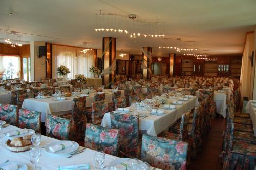 un salón de banquetes con mesas y sillas blancas en hotel lo sciatore en Cotronei