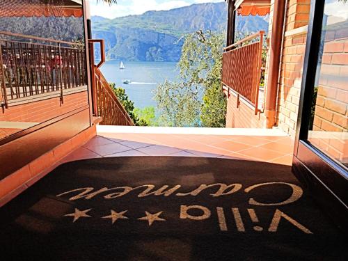 a room with a balcony with a view of the water at Hotel Villa Carmen in Malcesine