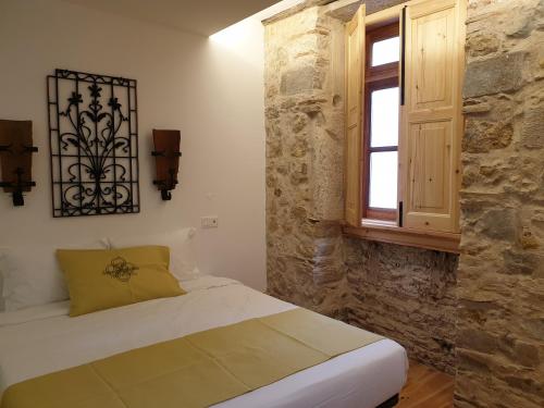 1 Schlafzimmer mit einem Bett mit einem Fenster und einer Steinmauer in der Unterkunft Casa da Baixa Downtown House in Coimbra