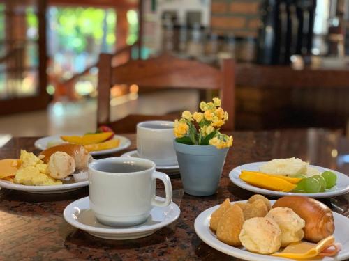 a table with plates of food and cups of coffee at Hotel São Sebastião da Praia in Florianópolis