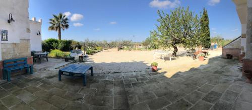 a patio with a table and benches in a yard at B&B Terre dì Montecoco in San Pancrazio Salentino