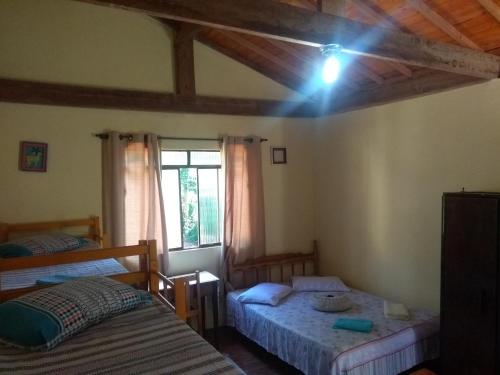 ein Schlafzimmer mit zwei Betten und einem Fenster in der Unterkunft Casa dois andares com área de churrasco em Ibitipoca in Conceição da Ibitipoca