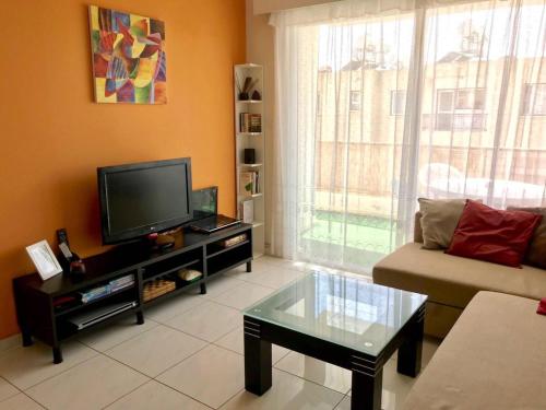 ein Wohnzimmer mit einem Sofa und einem TV in der Unterkunft Beautiful Apartment near the Sea in Paphos City