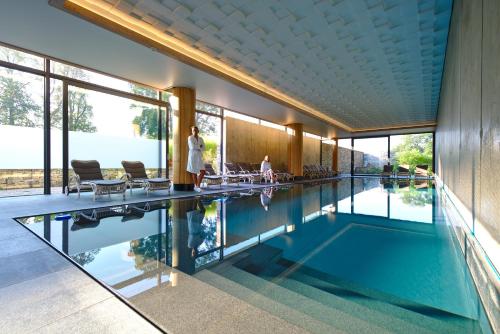 a swimming pool in a house with people standing around it at Domaine de Naxhelet in Wanze
