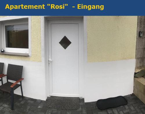 a white door of a building with a window and a chair at Miniappartement Zini in Lindlar