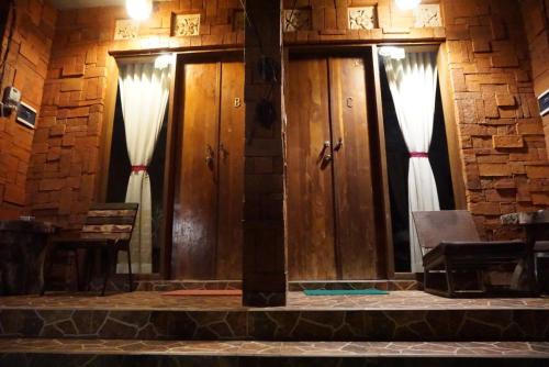 a set of wooden doors with curtains in a brick wall at Louto Dmell Villa & Guesthouse in Sanur