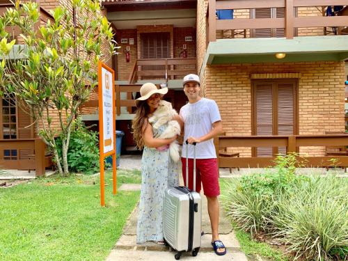 a man and a woman with a dog and a suitcase at Hotel São Sebastião da Praia in Florianópolis