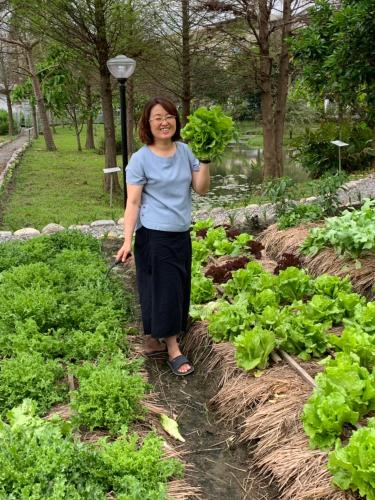 a woman standing in a garden holding lettuce at Yosemite Homestay in Yuanshan