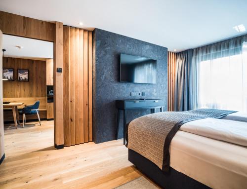 a bedroom with a bed and a desk and a television at Granbaita Dolomites in Selva di Val Gardena