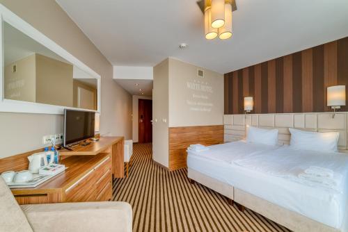 a hotel room with a bed and a television at Hotel White in Krynica Morska