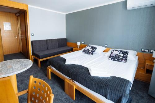 a room with a bed and a chair and a table at Hotel GH Kolinska in Bled