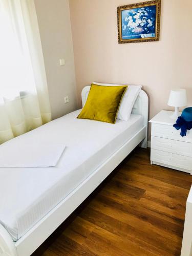 a white bed with a yellow pillow on it at Joy Hotel in Sarandë