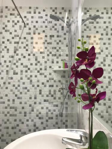a vase with purple flowers sitting on a sink at Joy Hotel in Sarandë