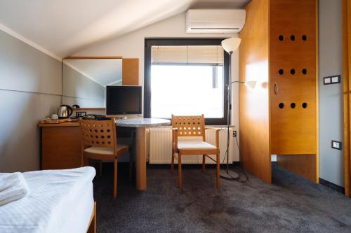 a bedroom with a desk with two chairs and a bed at Hotel GH Kolinska in Bled