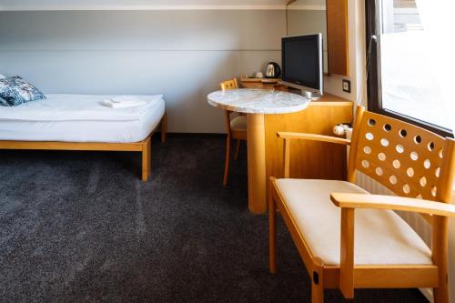 a room with a bed and a table and a tv at Hotel GH Kolinska in Bled
