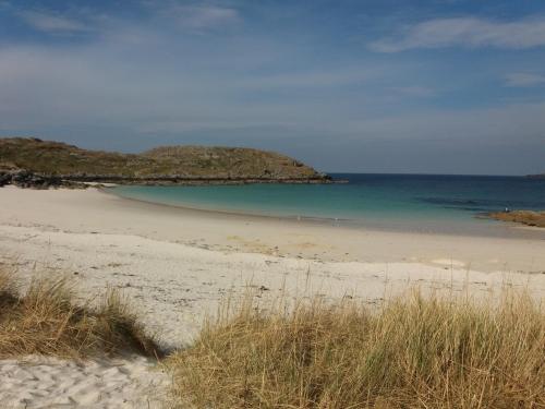 a sandy beach with a small island in the water at 3 St Gilbert Street in Dornoch