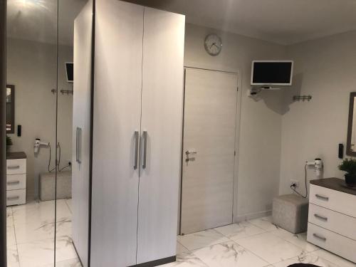 La salle de bains blanche est pourvue d'une douche et d'une horloge murale. dans l'établissement Marsascala Sea View Apartment & Penthouse, à Marsaskala