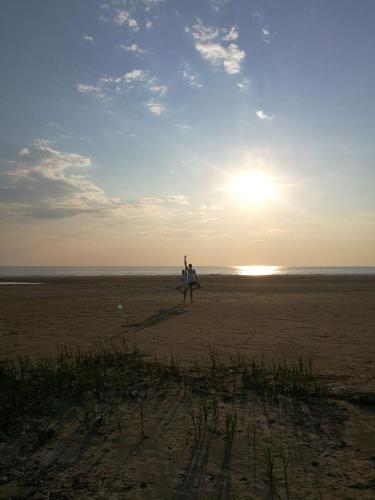 a person walking on the beach with a surfboard at Suurkivi Nature Escape in Häädemeeste