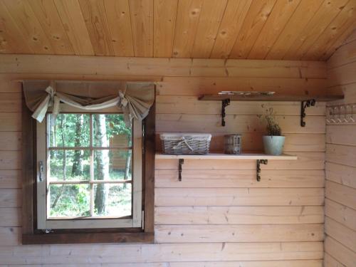 una ventana en una cabaña de madera con una cortina en Suurkivi Nature Escape, en Häädemeeste