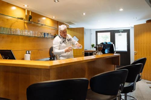 a man standing at a bar in a restaurant at Hotel GH Kolinska in Bled