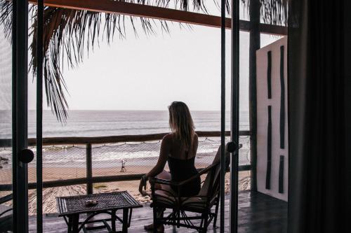 a woman sitting in a chair looking out at the beach at Baja Canoas Hotel in Canoas De Punta Sal