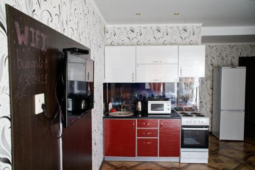 ゼリョンナヤ・ポリャナにあるТаунхаус Солнечная 40-8のキッチン(赤いキャビネット、白い冷蔵庫付)