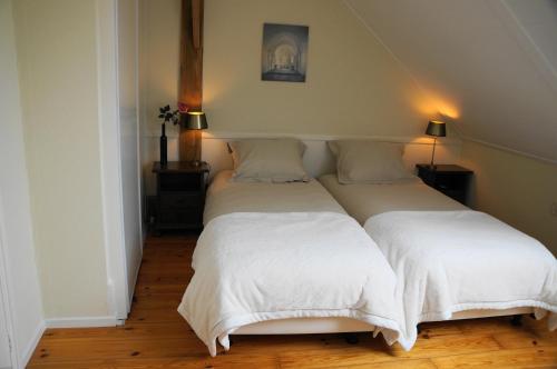 una camera con due letti con lenzuola bianche di 't Lankhof ad Aalten