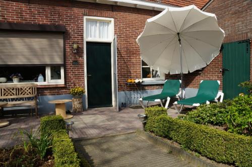 a patio with two chairs and an umbrella at 't Lankhof in Aalten