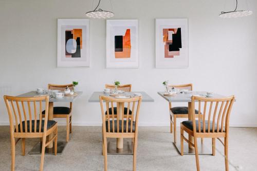 ein Esszimmer mit Tischen, Stühlen und Gemälden an der Wand in der Unterkunft meerzeit Hotel in Cuxhaven