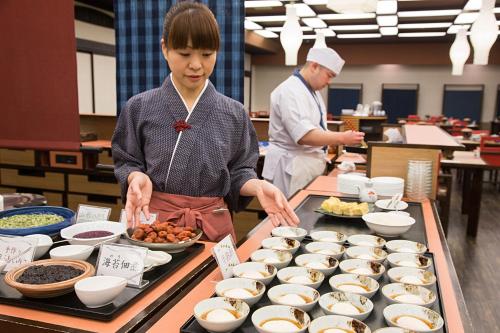 a woman standing in a kitchen preparing food at Tachibanaya in Tsuruoka