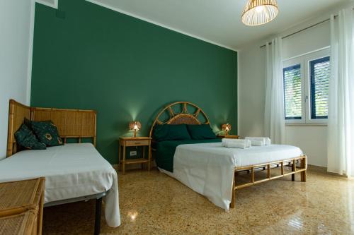 a bedroom with two beds and a green wall at Villa Aurora Mondello Addaura in Mondello