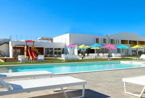 a pool with chairs and umbrellas and a playground at RIDE Surf Resort & Spa Peniche in Peniche