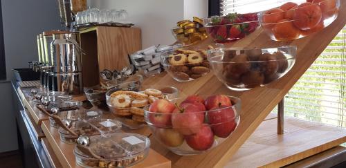 a wooden counter with bowls of fruit and pastries at Hotel GH Kolinska in Bled