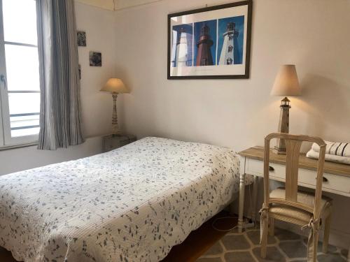 Un dormitorio con una cama, un escritorio y una silla. en Appartement Trouville Plage, en Trouville-sur-Mer