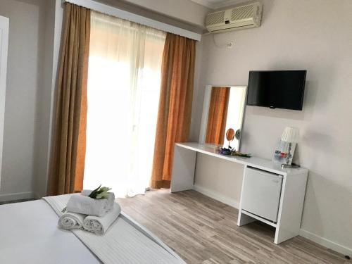 a room with a bed with a television and a desk at Joy Hotel in Sarandë