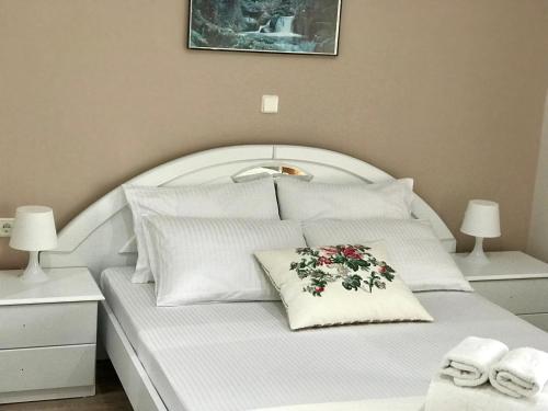 a white bed with a flower pillow on it at Joy Hotel in Sarandë