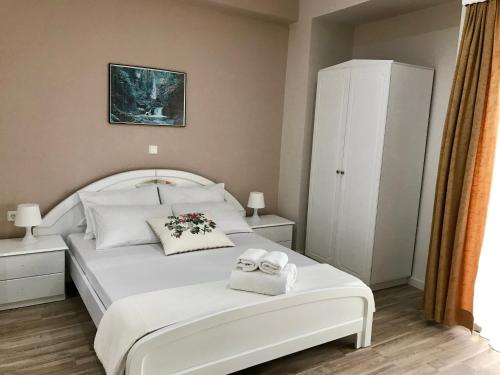 a bedroom with a white bed with towels on it at Joy Hotel in Sarandë