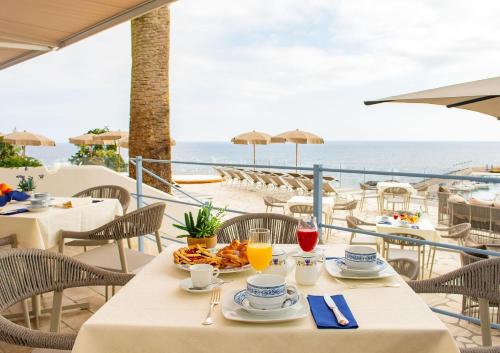 un tavolo con cibo e bevande su un balcone con vista sull'oceano di Hotel Gran Paradiso a Ischia